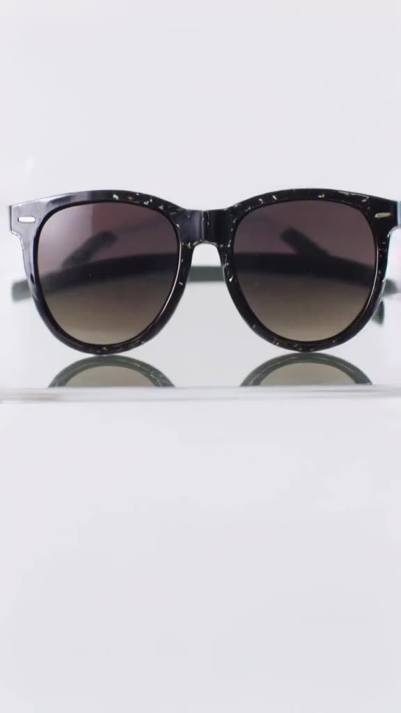 A pair of oversized sunglasses rests on a mirror. When the camera tilts down, confetti ca…
