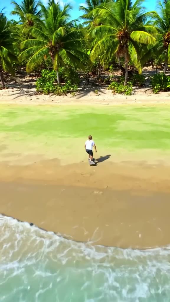 A skateboarder rides on a beach where the sand turns into soft, squishy green matcha powd…