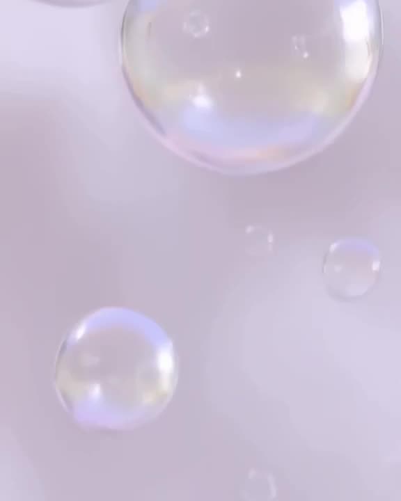 Soap bubbles float in zero gravity, popping one by one in slow motion. Soft pastel backgr…