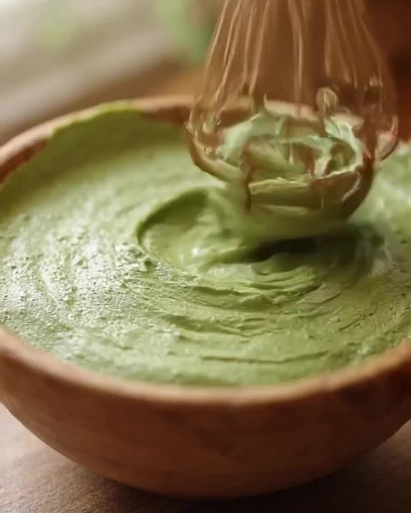 A sneaker crafted from layered matcha green tea mousse sits in a wooden bowl. A bamboo wh…