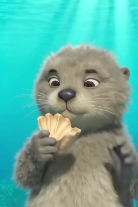 Close-up of a cute, fluffy sea otter in crystal clear turquoise water. It holds a seashel…