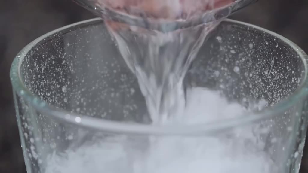 Ice cubes drop into a glass of soda, causing fizz and bubbles to rise rapidly. Condensati…