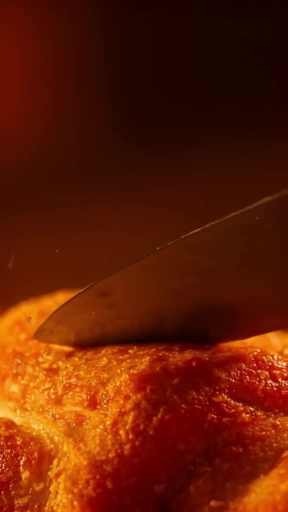 A croissant is being sliced by a tiny, invisible knife. Crumbs float up and turn into flo…