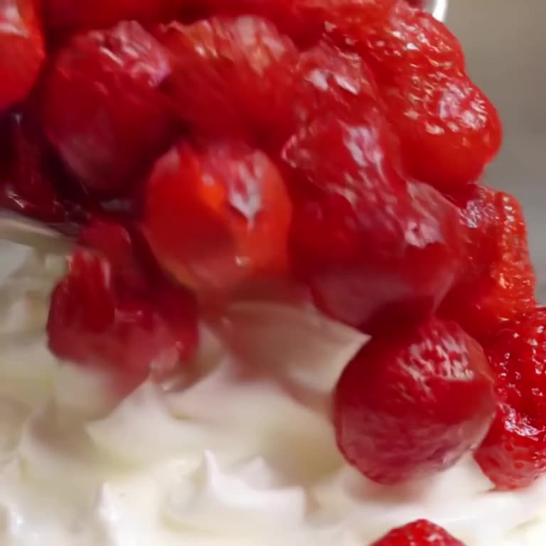 A giant strawberry rolls down a slope of whipped cream like a bowling ball, knocking over…