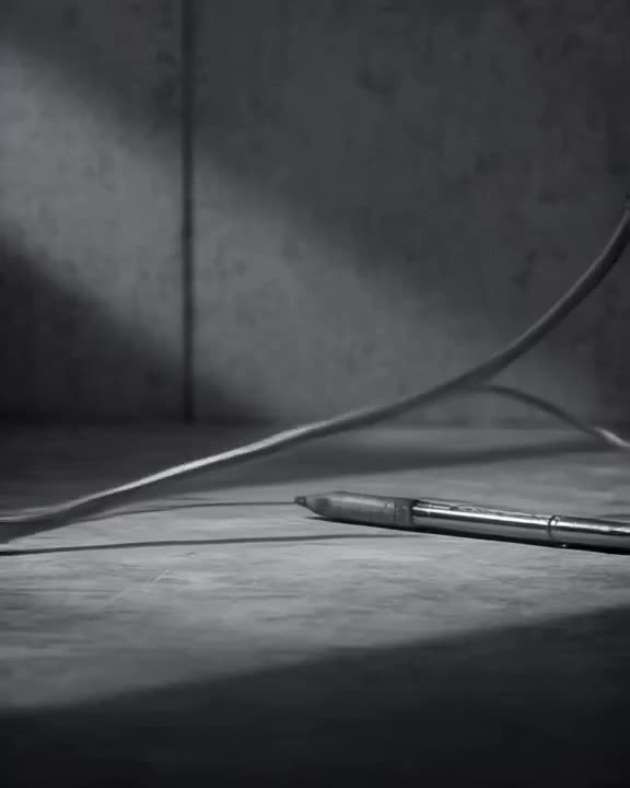 A microphone cable uncoils itself like a snake, slithering across a desk to grab a pen. I…