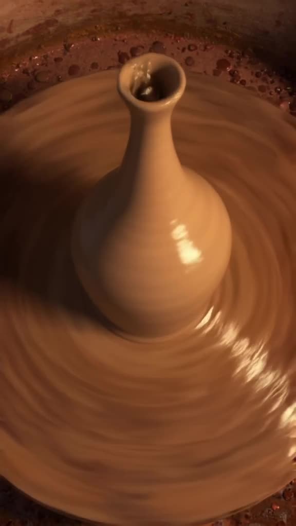 A pottery wheel spins rapidly, throwing a tall, slender vase that spirals upward infinite…