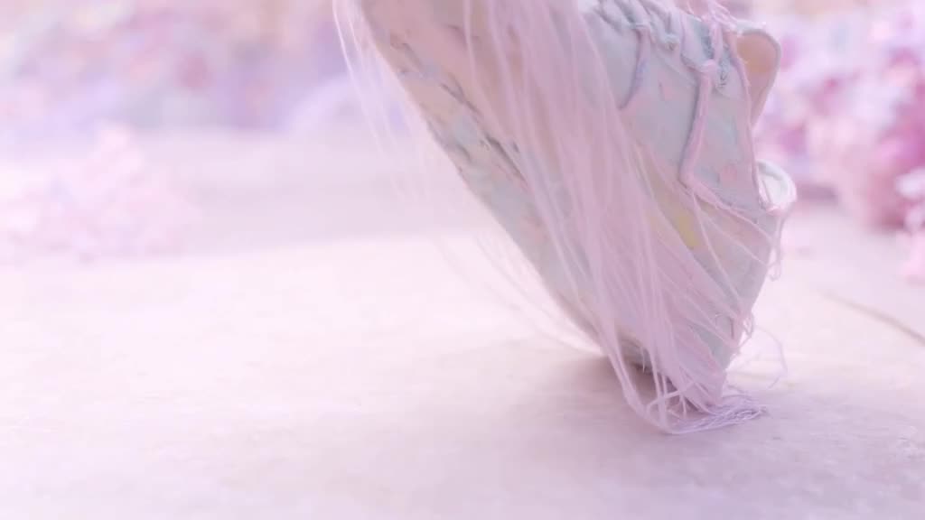 A sneaker made of spun sugar is lifted by a gentle breeze, unraveling into thin, sweet th…