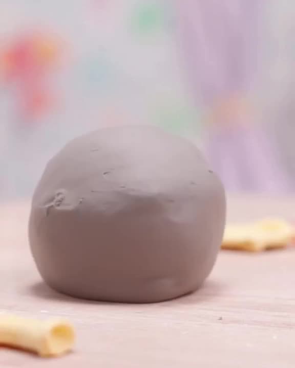 A clay ball of gray dough sits on a table, suddenly stretching and shaping itself into a …