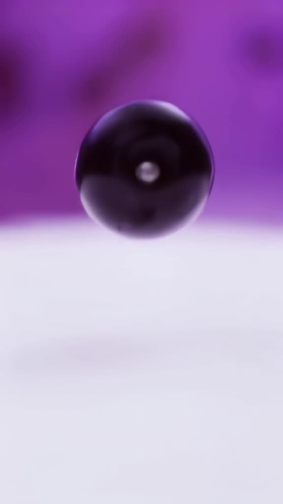 A single grape pops into the frame, revealing a miniature pearl inside. Macro lens shot w…