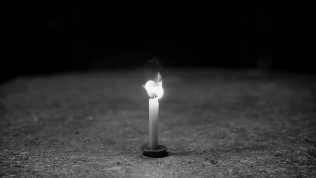 A lone candle flame on a stone table grows rapidly, its smoke forming the shape of a soar…