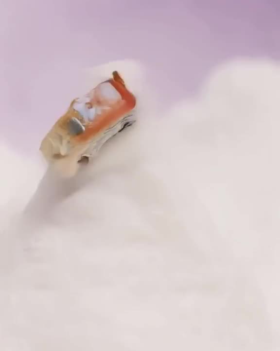 A miniature clay-model race car crashes into a soft, fluffy marshmallow mountain, bouncin…