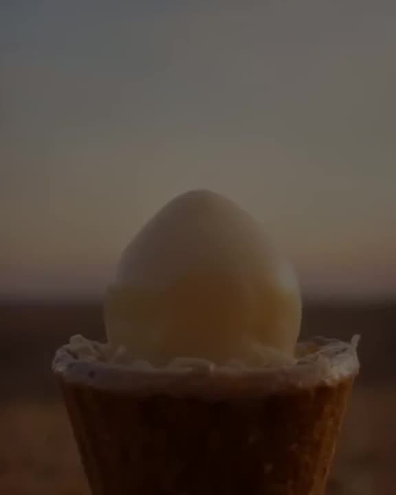 An ice cream cone melts in reverse: puddles rise up, swirls form, and scoops stack perfec…
