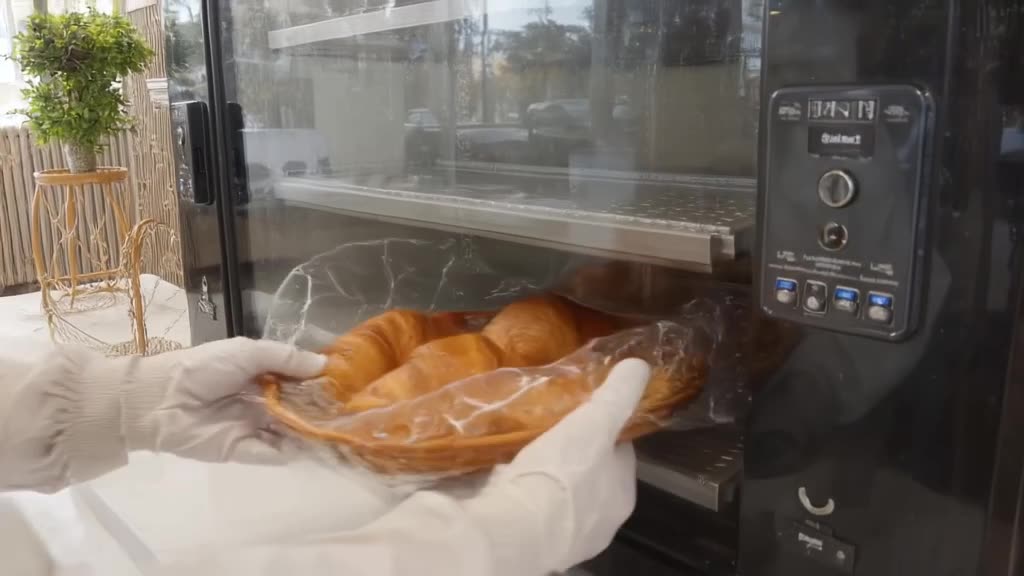 A vending machine dispenses a single, perfect croissant and a hot cup of coffee simultane…