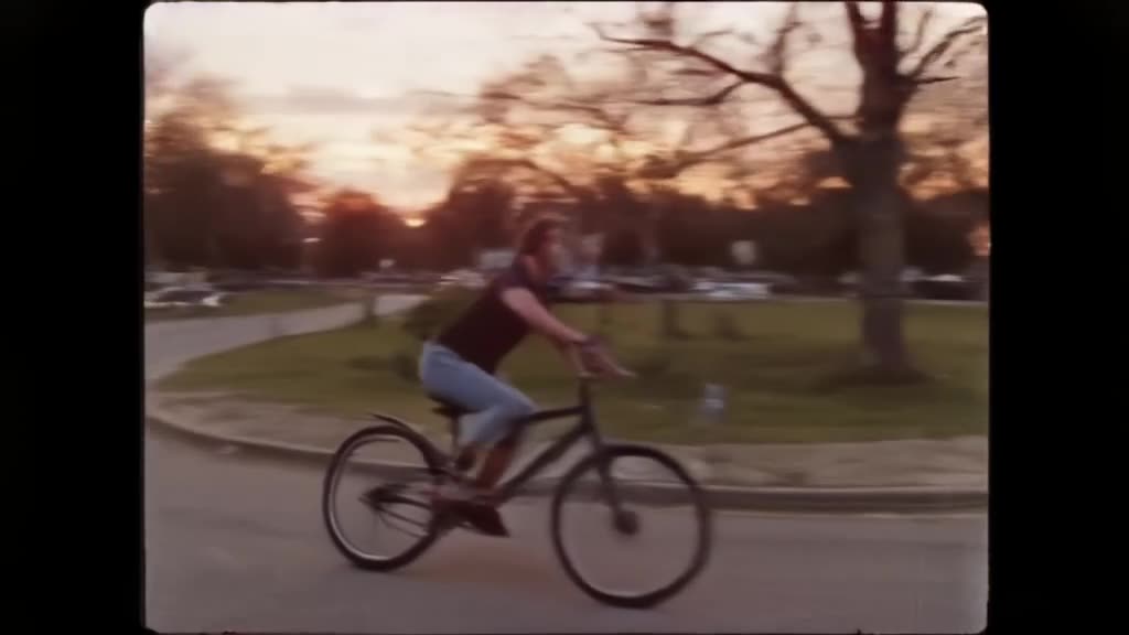 Vintage VHS footage of a bike riding at dusk. The bike turns a corner and transforms into…