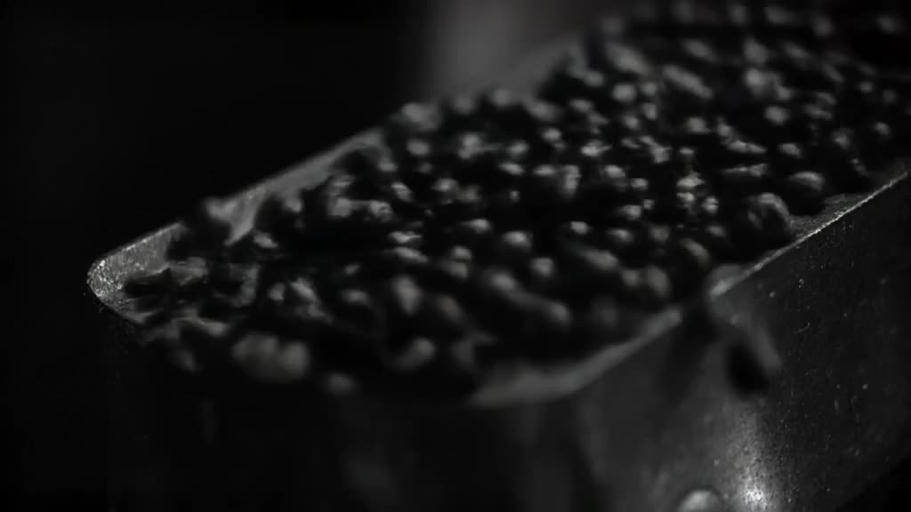 A slow-motion shot of coffee beans falling into a grinder. The beans bounce and settle pe…