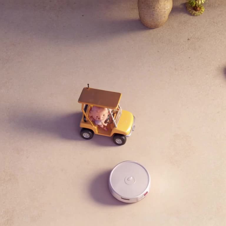 A robot vacuum tries to wash a miniature golf cart by bumping into the tires repeatedly. …