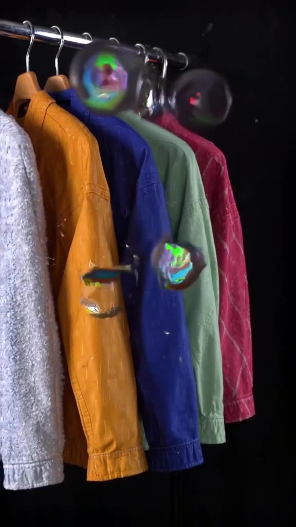 A jacket hangs on a rack. Suddenly, all the buttons pop off simultaneously, flying in slo…