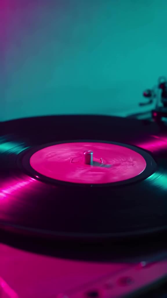 Close-up of a vinyl record slowly rotating under a neon pink spotlight. Tiny hands pop ou…