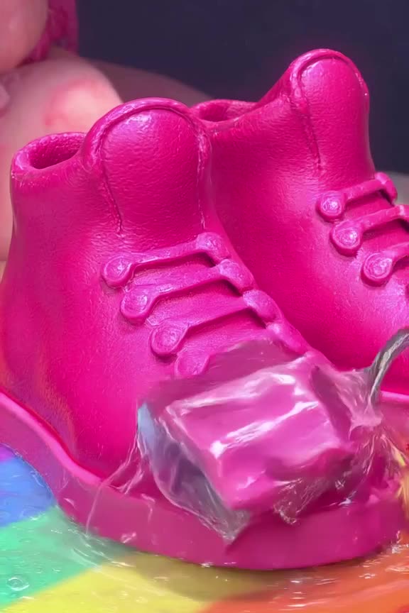 A vibrant neon pink sneaker sits on a bed of rainbow Jell-O. A spoon scoops out a perfect…