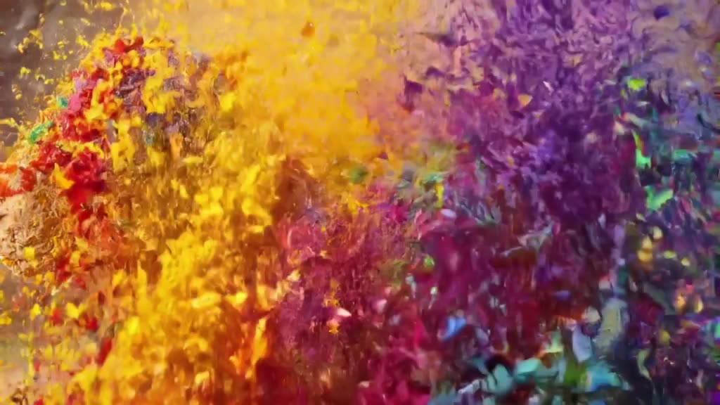 A clay sculpture of a animal is covered in colorful powder. A burst of air blows the powd…