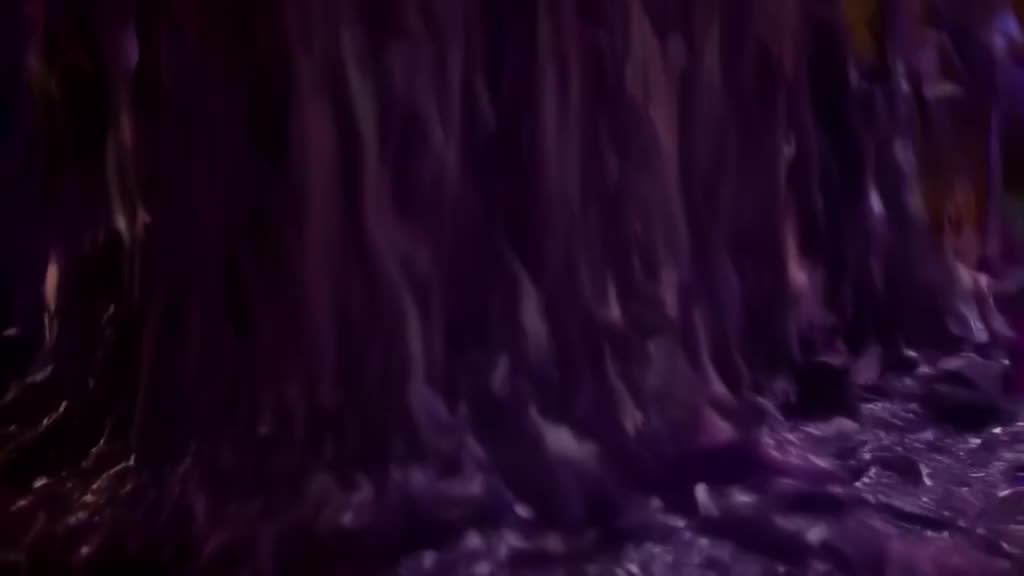 A skateboard rolls onto a surface of thick, purple slime. The wheels sink in, creating pe…