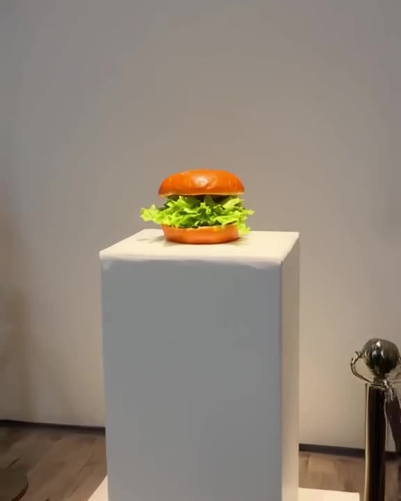 A burger is placed on a pristine white pedestal in a minimalist gallery. Spotlights highl…