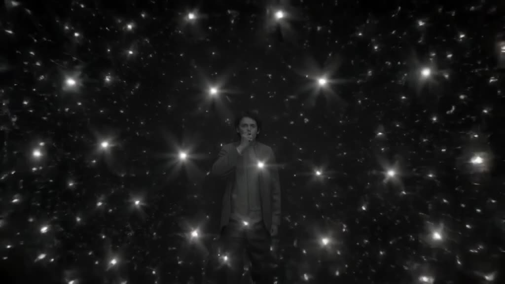 Drone shot pulls back from a tiny person blowing a massive glass sphere in a dark room. T…