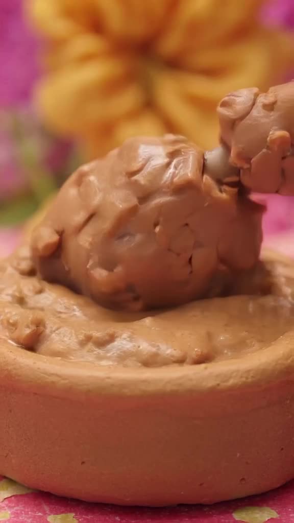 A claymation hand scoops ice cream, but the scoop is made of clay that squishes realistic…
