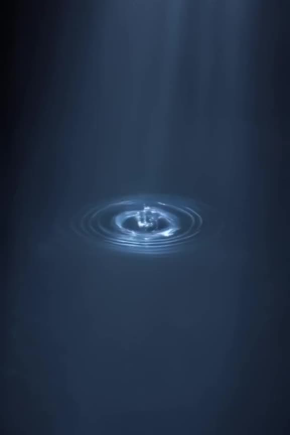 Cinematic macro shot of ink drop hitting water. The ripples form a perfect eye that winks…
