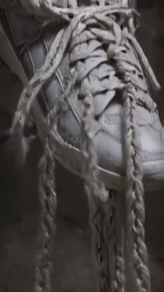 A pair of sneakers on a rack unzips their laces. The laces unravel into a thick, braided …