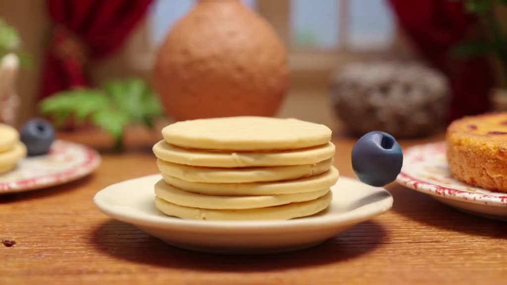 A stack of pancakes wobbles on a plate. A single blueberry rolls in from the side, lookin…
