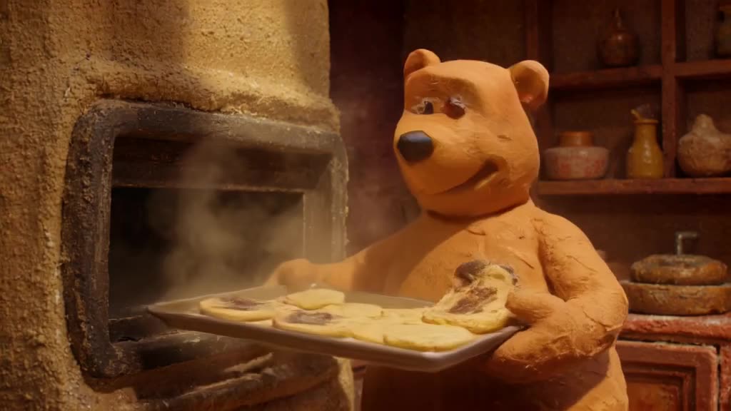 A bear baker pulls a tray of cookies out of the oven. One cookie is burnt, and it hides i…